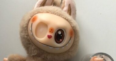 Tan plush toy with bunny ears and a quirky face.