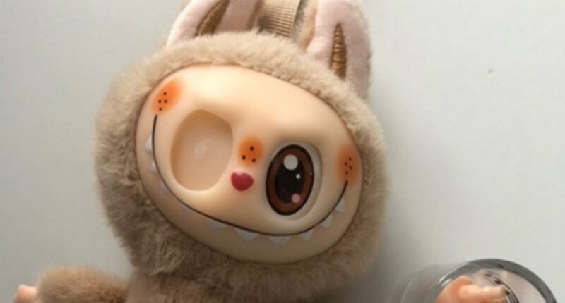 Tan plush toy with bunny ears and a quirky face.