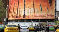 Billboard depicting Iranian ballistic missiles; text reads "Israel is weaker than a spider's web".