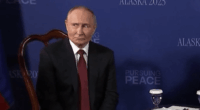 Vladimir Putin sitting at a table.