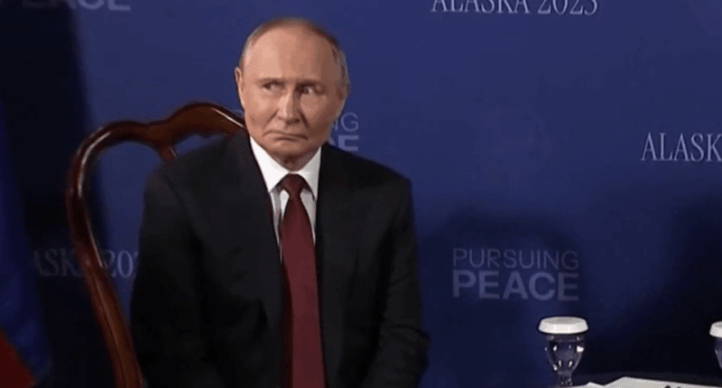 Vladimir Putin sitting at a table.