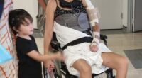 Woman in wheelchair with neck brace and arm sling, surrounded by family.