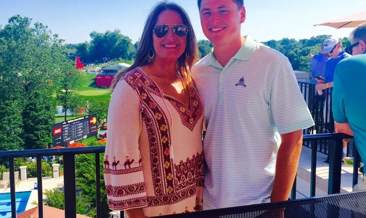 Woman and young man smiling for a photo on a patio overlooking a golf course.