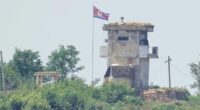 A soldier stands at a North Korean military guard post flying a national flag, seen from Paju, South Korea, in June 2024.