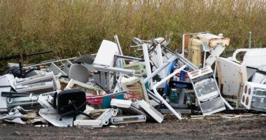 Pile of discarded appliances and furniture at a rubbish dump.