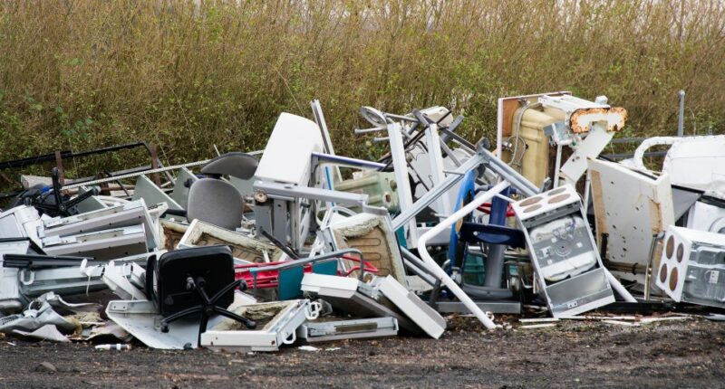 Pile of discarded appliances and furniture at a rubbish dump.