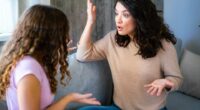 A mother and teenage daughter arguing on a couch.