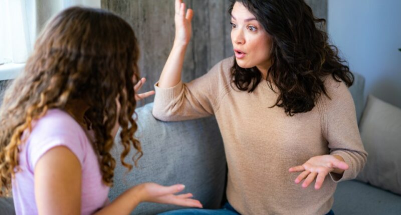 A mother and teenage daughter arguing on a couch.