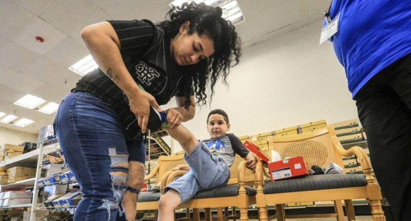 Isaiah Moctezuma, 6, tries on a new pair of New Balance tennis shoes with help from his mother, Kat, at Shoe Stop while shopping for back-to-school shoes provided by the Danheiser Fund for Kids, Saturday, Aug. 2, 2025, in Owensboro, Ky. (Greg Eans/The Messenger-Inquirer via AP)