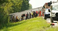 First responders assisting victims at the scene of a rolled-over tour bus.