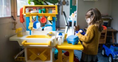 A little girl playing with a toy kitchen.