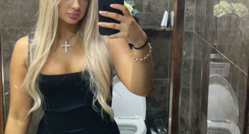 Selfie of a blonde woman in a black dress.