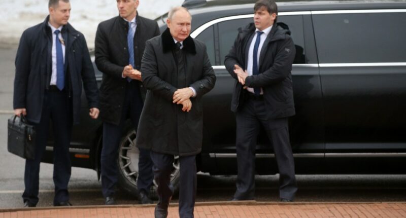 Vladimir Putin with bodyguards near a car.