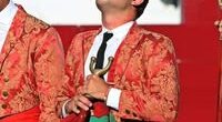 A young bullfighter in a red jacket.