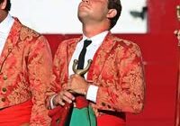 A young bullfighter in a red jacket.
