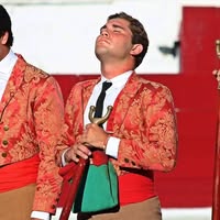 A young bullfighter in a red jacket.