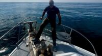 Man standing on the bow of a boat at sea.