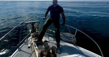 Man standing on the bow of a boat at sea.