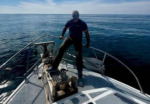 Man standing on the bow of a boat at sea.