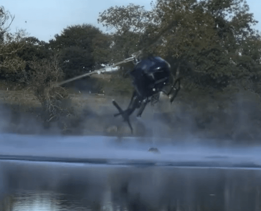 Helicopter spraying water over a lake.