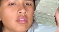 A USPS worker with a stack of cash next to her face.