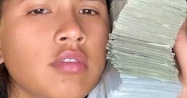 A USPS worker with a stack of cash next to her face.