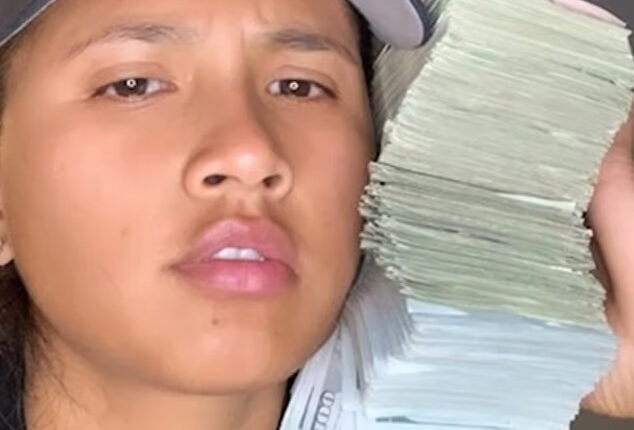 A USPS worker with a stack of cash next to her face.
