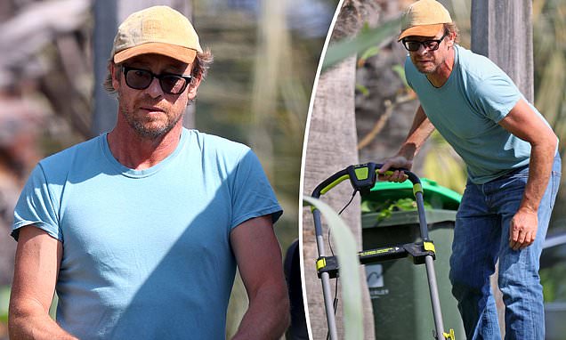 Simon Baker works up a sweat as he mows the lawn outside his home