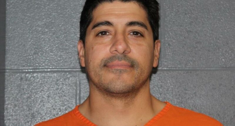 Mugshot of a man in an orange jumpsuit.