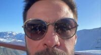 Selfie of a man wearing sunglasses, with snowy mountains in the background.