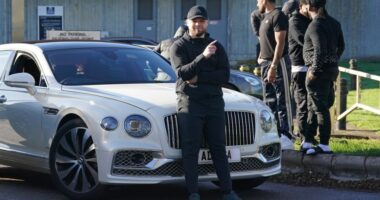 Man released from prison posing by a white Bentley.
