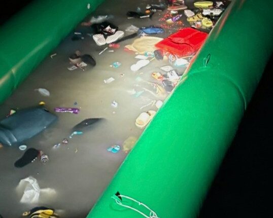 Partially flooded dinghy filled with debris following a rescue operation.