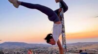 Woman performing a handstand on a flagpole in Cappadocia, Turkey.