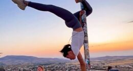 Woman performing a handstand on a flagpole in Cappadocia, Turkey.