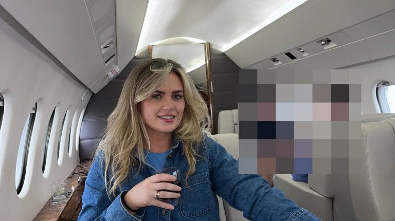 Woman sitting in a private jet, holding a drink.