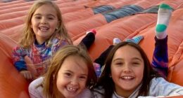 Three young girls smiling on a large inflatable.