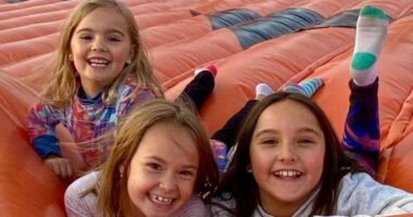 Three young girls smiling on a large inflatable.