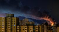 Smoke rises over Kyiv apartment buildings at night following Russian missile strikes.