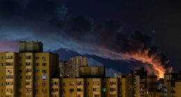 Smoke rises over Kyiv apartment buildings at night following Russian missile strikes.