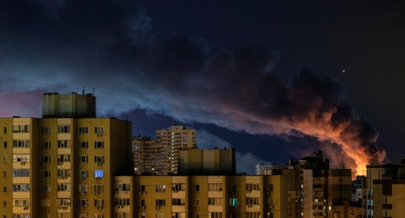 Smoke rises over Kyiv apartment buildings at night following Russian missile strikes.
