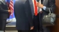 Putin and Trump speaking with others in a hallway.