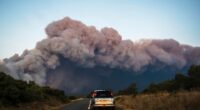 Cars drive past a fast-moving wildfire in a Mediterranean region of France near the Spanish border is pictured Tuesday Aug.5, 2025. (Richard Capoulade/UGC via AP)