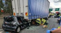 A woman in her 20s was trapped in a car which was crushed between two trucks after a horror crash on a Sydney motorway.