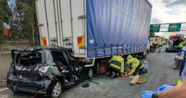 A woman in her 20s was trapped in a car which was crushed between two trucks after a horror crash on a Sydney motorway.