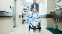 Pregnant woman in a wheelchair being pushed by a man down a hospital corridor.