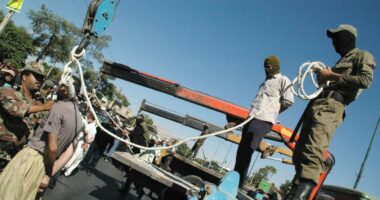 Masked Iranian soldiers and government employees preparing to publicly hang a condemned man in Shiraz.