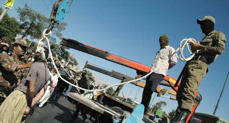 Masked Iranian soldiers and government employees preparing to publicly hang a condemned man in Shiraz.