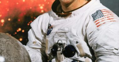 Portrait of Jim Lovell, Apollo 13 commander, in a spacesuit holding a moon globe.