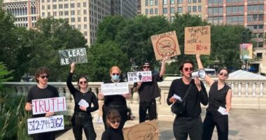 Protestors holding signs demanding a man be freed from a bean-shaped structure.