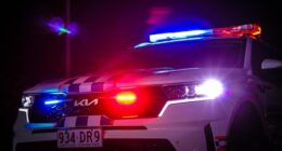 A QLD Kia Police car at night with its sirens on